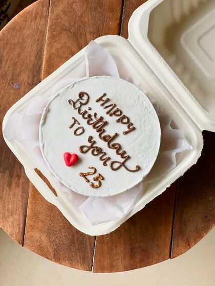 A classic and simple birthday bento cake. The white frosting provides a clean canvas for the "Happy Birthday to you" message, with the age "25" and a single red heart.