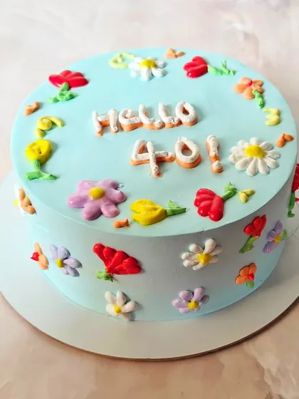 "Hello 40!" A cheerful and colorful cake to welcome a new decade. This design is covered in hand-piped buttercream flowers in a variety of bright colors.