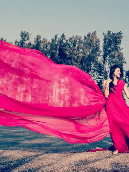 A beach pre-wedding shoot gets a vibrant upgrade with this hot pink trail gown. The lightweight fabric catches the wind beautifully, creating a dynamic and joyful photo as the couple walks along the shore.