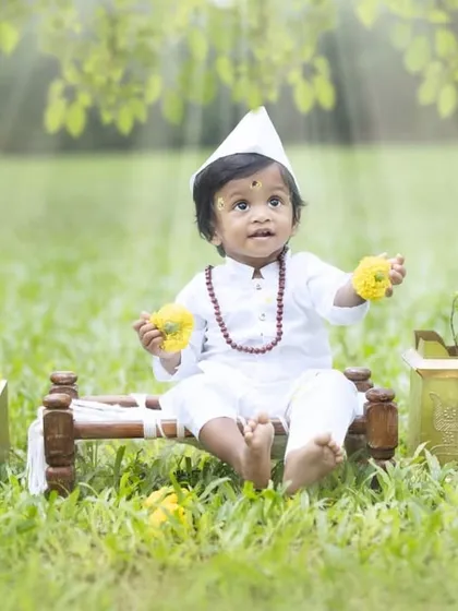 This little Varkari is holding flowers as an offering. The details in this themed cultural photoshoot, from the props to the soft lighting, create a truly dreamy and divine image.