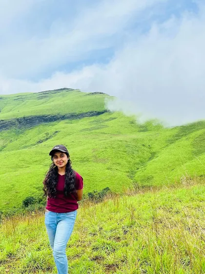 A smiling trekker poses against the beautiful backdrop of the Netravathi hills.