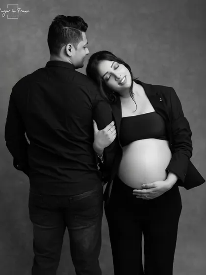 A modern and chic black and white maternity portrait. The mom-to-be rests her head on her partner's shoulder, creating a look of serene confidence.