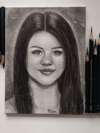 My finished graphite and charcoal portrait of Selena Gomez, drawn on canvas. The canvas texture gives the final piece a unique, slightly raw and painterly feel.