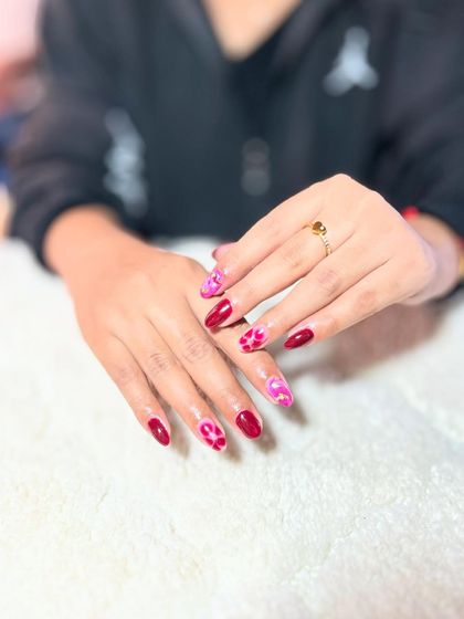 Another view of the red and pink leopard print nails, showing the full set. Consistency in pattern work is a skill we focus on.