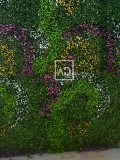 A full view of a custom-designed floral vertical garden. The swirling patterns of pink, yellow, and white flowers create a vibrant and artistic feature wall.