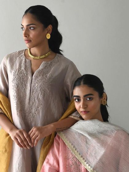 Two models showcasing understated elegance in muted-tone kurtas with delicate self-embroidery.