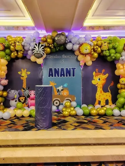 A closer look at the main stage for the jungle-themed mundan, showing the details of the balloon arch with animal print and foil balloons.