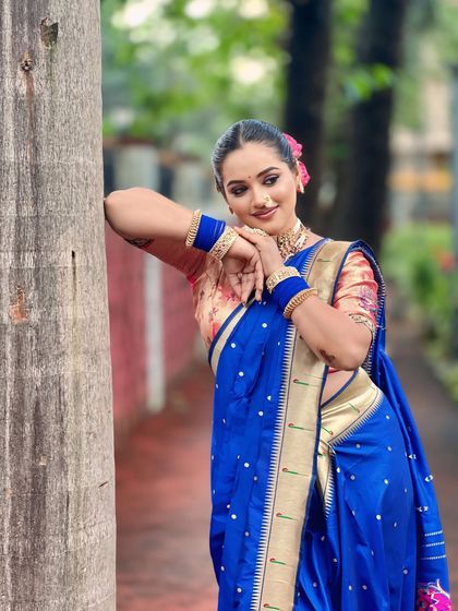 A playful pose showing the beautiful border of the blue Paithani saree and the intricate details of the jewellery.