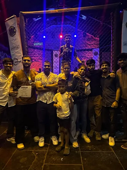 The team celebrating under the bright lights of the cage. Four gold medals and one silver. Every fight is a learning experience, and we'll be back stronger.