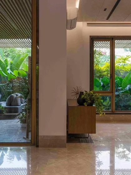 A seamless transition from a marble-floored interior to a verdant outdoor patio. The design uses large glass panels to dissolve the barrier between inside and out, making the garden a constant presence.
