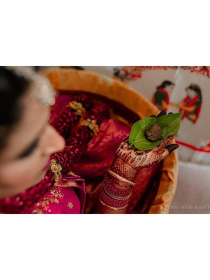 A close-up of a bride holding a betel leaf, a significant element in Hindu wedding ceremonies, symbolizing prosperity and freshness.