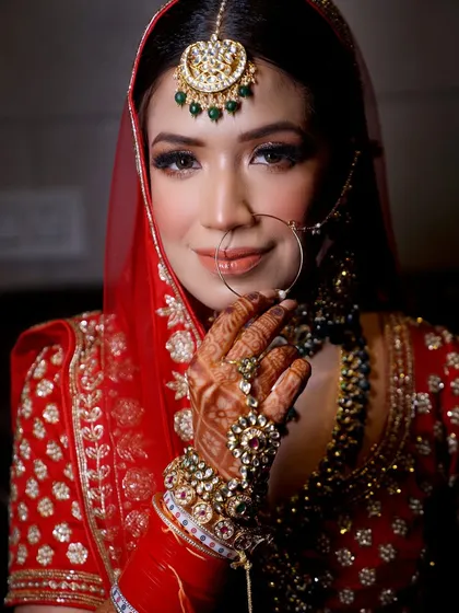A beautiful portrait capturing the bride's gentle smile and the sparkle of her traditional jewelry, including her nath and maang tikka.