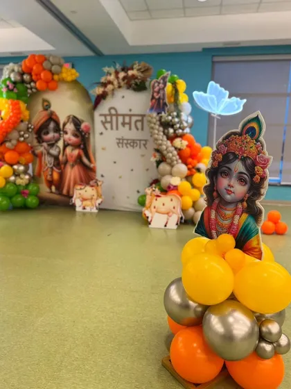 A detailed shot of the Seemantha Sanskar decor, focusing on a large cutout of baby Krishna placed on a balloon cluster. In the background, you can see the main stage with its colorful balloon arch and custom backdrops.