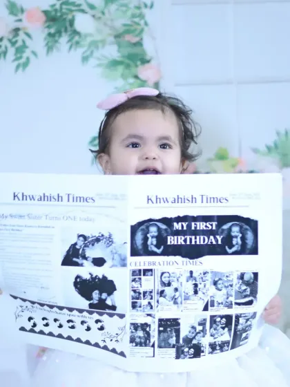 A close-up of the baby holding their personalized "First Birthday" newspaper, a creative and memorable prop.