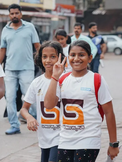 Two girls flashing a peace sign, enjoying the walk through their town.