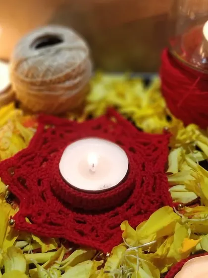Our star-shaped crochet diya holder glowing amidst a bed of yellow flower petals. This image captures the beautiful and traditional way our products can be used.