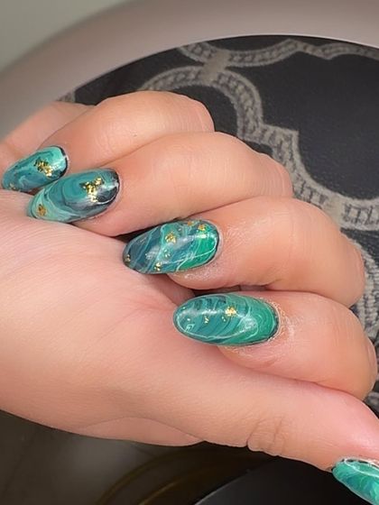 Forest nymph vibes with these green marble nails, featuring swirls of different shades of green and gold foil flakes.