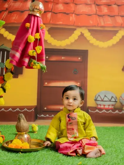 A smiling baby boy in his festive attire, seated next to the traditional 'puja thali' for the Gudi Padwa celebration.