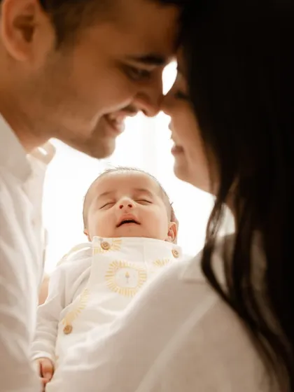 A close, intimate shot focusing on the smiling newborn nestled between their parents. It’s a moment of pure, sleepy bliss.