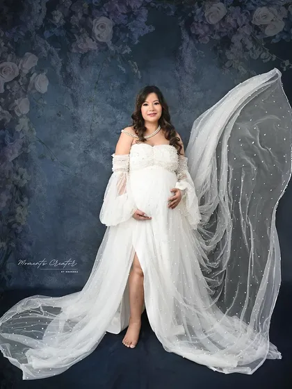 An ethereal portrait with a sparkling fabric toss. The sheer, glittery fabric flows behind the mom-to-be, creating a magical and dreamy effect.