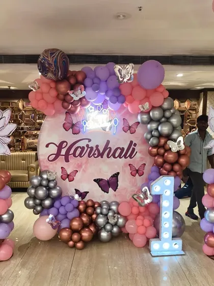 I created this enchanting butterfly and fairy theme for a first birthday party. The decor features a custom backdrop, character cutouts on balloon pillars, and a mix of chrome and pastel balloons.