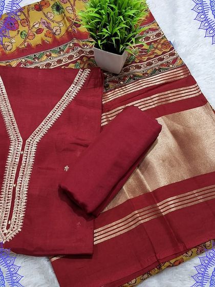 A rich maroon unstitched suit set with a gota work neckline. It is paired with a beautiful Kalamkari print dupatta with a traditional design and zari border.
