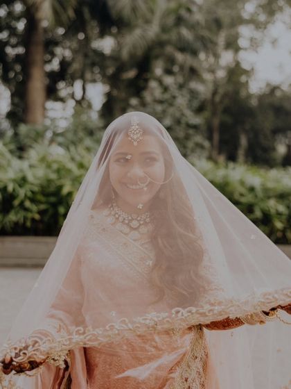 A soft and dreamy portrait of the bride peeking through her veil, her smile lighting up the frame.