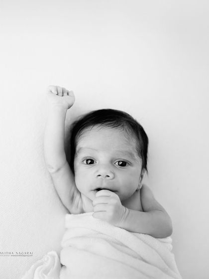 A minimalist black and white portrait of a two-week-old baby. The clean background and simple wrap put all the focus on their emerging personality.