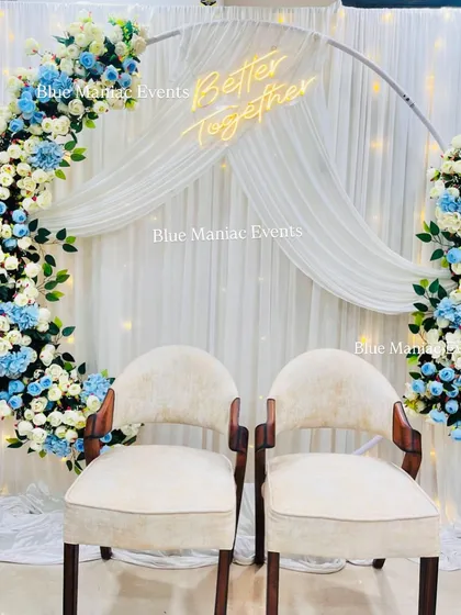 A stylish Roka setup with a circular frame decorated in white and blue florals. The addition of two classic wooden chairs provides a sophisticated seating option for the couple.