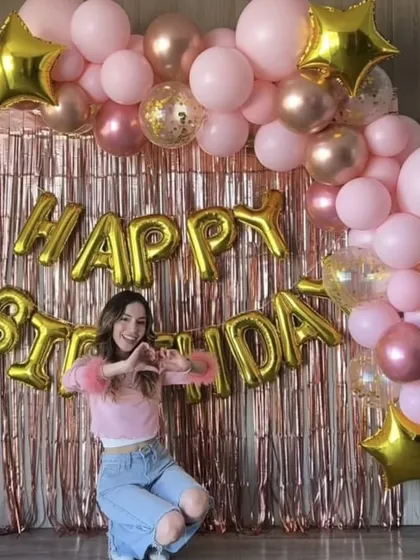 This trendy rose gold theme is perfect for creating a chic photo corner. The setup includes a shimmering fringe backdrop, a balloon garland with pastel pink and metallic rose gold balloons, and large "Happy Birthday" foil letters.