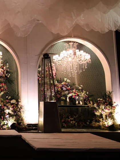 Another view of the arched stage backdrop, showing the interplay of light, florals, and architectural elements.
