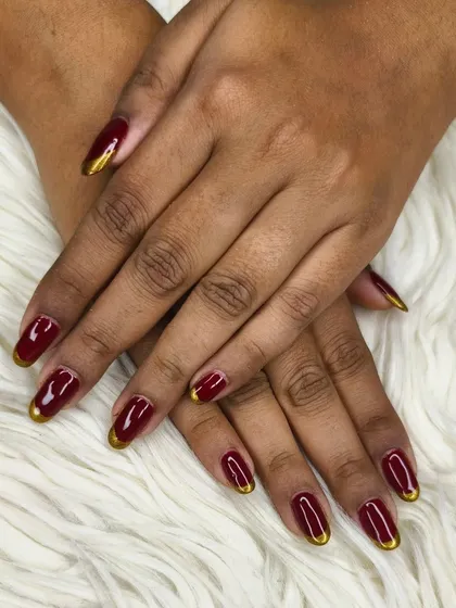 A bold and regal look with rich maroon gel polish and striking gold French tips on almond-shaped extensions. Perfect for festive occasions.