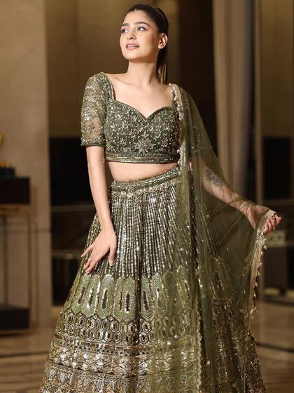 Another beautiful shot of the olive green lehenga, highlighting the way the golden embroidery catches the light. It's a sophisticated and elegant choice for any formal occasion.