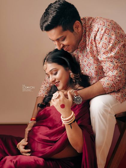 An intimate portrait showing the couple's deep connection. His gentle embrace from behind provides a sense of safety and love as they both look down with affection.