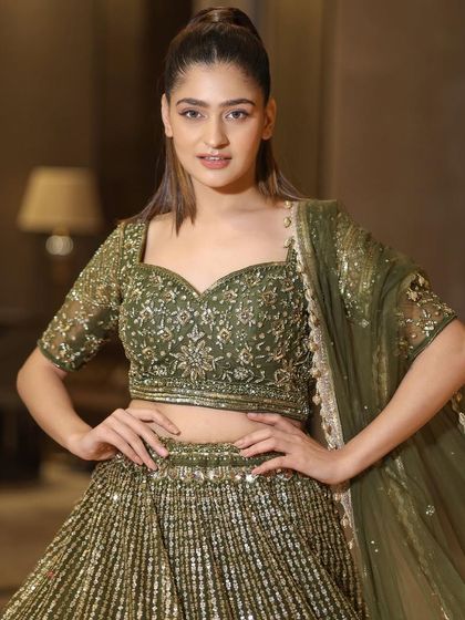 A close-up portrait highlighting the beautiful embroidery on the blouse and the model's confident smile. This lehenga is a true classic.