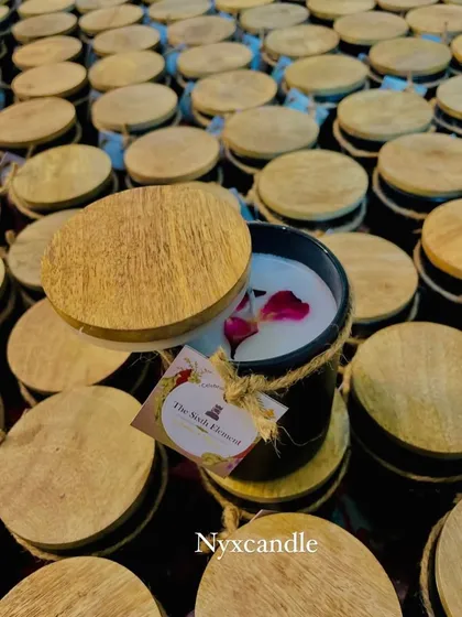 Another view of our black jar candle with a wooden lid, created for a white-labeling order. The candle is topped with rose petals, adding a premium touch to the final product.