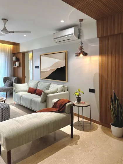 This living room showcases a perfect balance of elements. The soft, neutral sofa is grounded by a dark wood media console and accented with warm, rust-colored pillows.