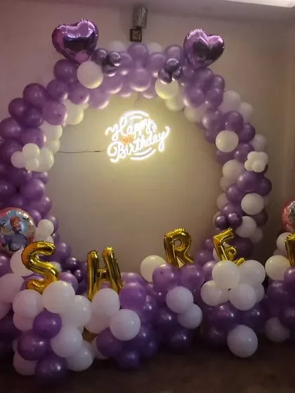 A personalized birthday ring backdrop. We used purple and white balloons, a neon sign, and the birthday person's name in foil letters to create this custom photo booth.