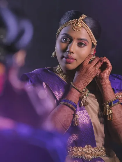 A minimalistic yet elegant muhurtham look for Priya. The focus is on clean lines and letting her natural beauty shine through her purple and gold saree.