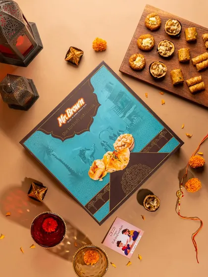 A festive flat lay for Mr Brown bakery's Baklava gift box. The composition includes traditional elements like diyas and marigolds to create a celebratory mood for Rakhi or Diwali gifting.