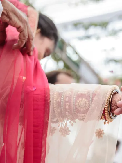 A close-up, artistic shot focusing on the traditional tying of the knot (gathbandhan), symbolizing the sacred union of the couple.