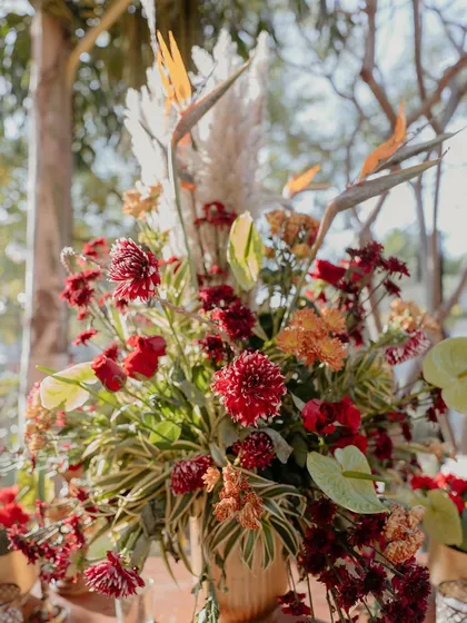 Another beautiful floral arrangement from the 'Regal Rustic Reverie' wedding, combining fresh red flowers with dried elements for a rich, textured look.