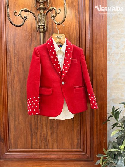 A statement in red velvet. This jacket features playful polka-dot details on the lapel and cuffs, a custom touch that adds a whimsical flair to a classic design.