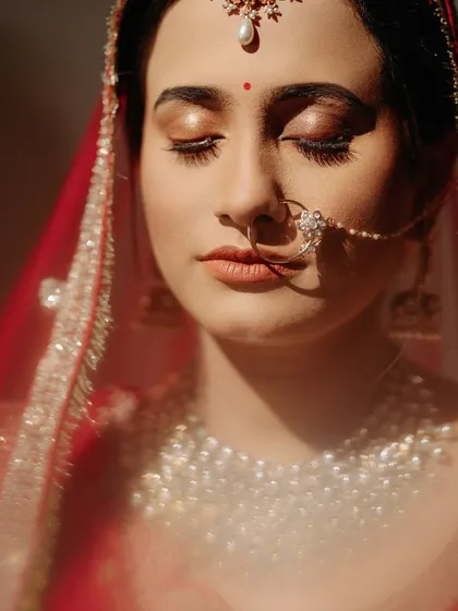 A sunlit close-up of the bride, her eyes closed in a moment of peace, highlighting her glowing makeup and jewelry.