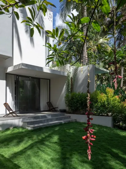 A quiet sit-out area on the east side of the house, perfect for enjoying the morning sun. The simple steps and patio create a gentle transition from the interior living space to the manicured lawn.