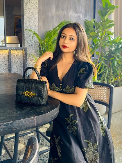 A classic black dress with puff sleeves and delicate green embroidery. Paired with a structured bag and a bold red lip, it's a timelessly elegant look for a dinner or event.