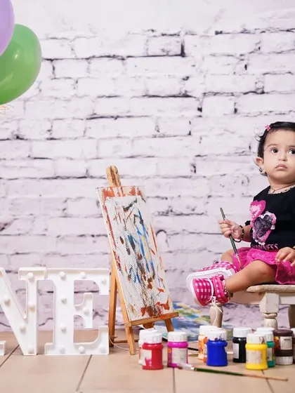 A little artist at work! This creative first birthday studio shoot features a mini easel, paints, and balloons, capturing a fun and colorful moment for a one-year-old.