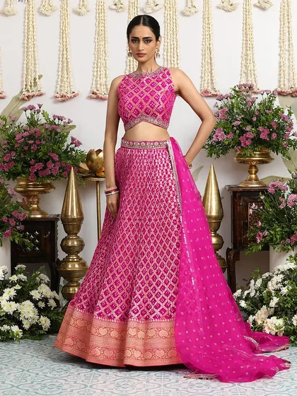 The sheer dupatta, with its delicate buti work, adds a final touch of grace to this stunning fuchsia lehenga. It is the perfect accessory to complete your festive look.