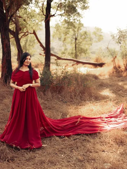 A full view of the red gown with its train laid out, showcasing the sheer amount of beautiful fabric you get to play with during your maternity rental.
