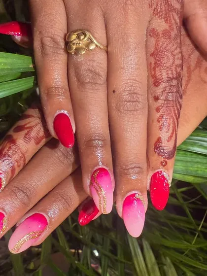 A full view of the vibrant pink and red ombre nails, showing how the colors blend together. The gold line art adds a touch of elegance.